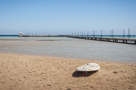 Sup boards on the sand of an empty beach / Surfboards standing upright in bright sun on the empty beachの写真素材