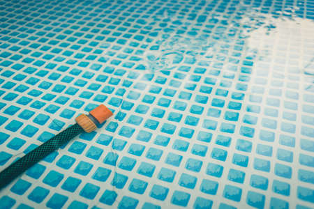 hose at the bottom of the pool / green hose at the bottom of the blue poolの写真素材