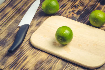 Sliced ââlimes with a white bladed knife on a wooden table. Top view.の写真素材