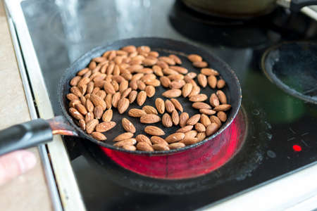 Almonds are fried in a skillet on a hot stove. top view.の写真素材