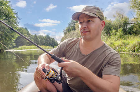 Portrait of a young man in a boat with a spinning rod.の写真素材