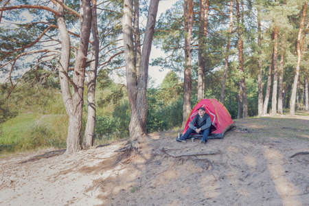Man sitting in the forest near the tent. outdoor camping.の写真素材