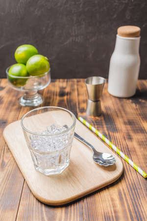 Ice for a cocktail and limes in glass on a wooden table. Making a cocktail.の写真素材