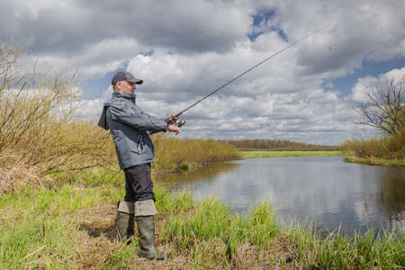 Fisherman throws spinning rod on the river bank. Autumn fishing.の写真素材