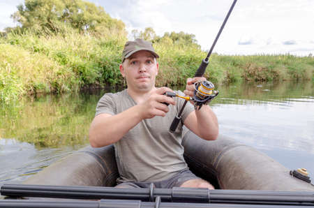 Portrait of a young man in a boat with a spinning rod.の写真素材