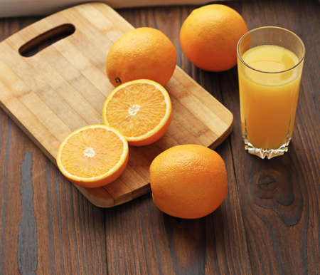 Oranges and a glass of orange juice on a wooden tableの写真素材
