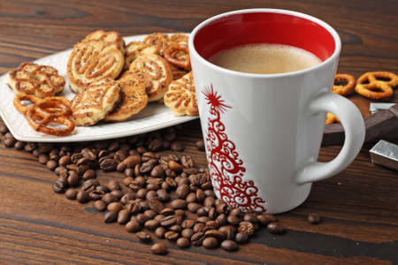 A cup of coffee, grains of coffee and cookies on a wooden table.の写真素材