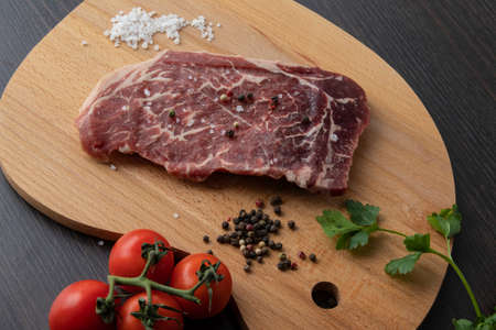 Raw beef steak with spices on a dark board. View from above.の写真素材