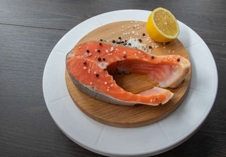 Raw salmon steak cooked for cooking. Top view on a black wooden table.の写真素材