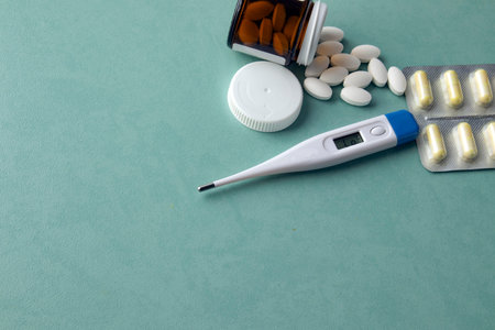 hermometer on a turquoise table, pills, medicine. Treatment concept