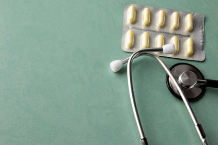 Thermometer on a turquoise table, stethoscope, medicine. Treatment conceptの写真素材