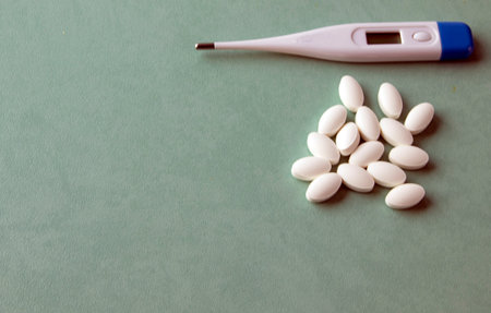 Thermometer on a turquoise table, pills, medicine. Treatment concept