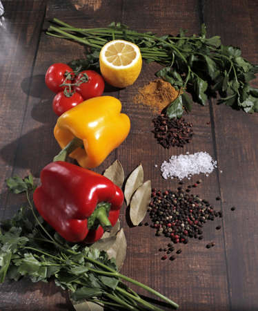 Multicolored peppers, branch of fresh tomatoes cherry cherry, pasta spinach fettuccine, parsley, slice of lemon and spices on a old board. Top view, with copy spaceの写真素材
