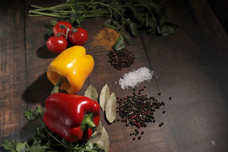 Multicolored peppers, branch of fresh tomatoes cherry cherry, pasta spinach fettuccine, parsley, slice of lemon and spices on a old board. Top view, with copy spaceの写真素材