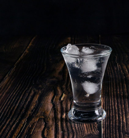 Vodka in glasses and ice on an old wooden table, closeupの写真素材