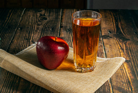 Apples in a basket on a wooden table on a black background, a glass of apple juice.の写真素材