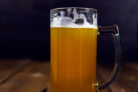 Glass of cold unfiltered thick light beer on rustic wooden table