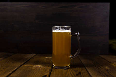 Glass of cold unfiltered thick light beer on rustic wooden tableの写真素材