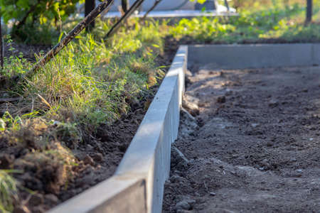 Installation of the Curb before laying the paving slabs. Reconstruction of the sidewalk and replacement of old curbs. Repair of the sidewalk. Selective focus.の写真素材