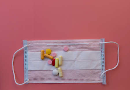Disposable medical face mask, different colors and pill shapes. On a pink background. Antiviral mask for protection against flu, coronavirus diseases.の写真素材