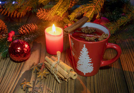 view of a table with a Christmas candle, hot mulled wine, with spices and fruits on a wooden rustic table background with fir branches. Traditional hot drink for Christmas.の写真素材