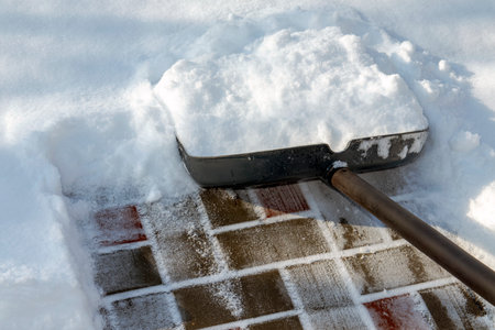 Manual snow removal from the sidewalk with a shovel in the snow.の写真素材