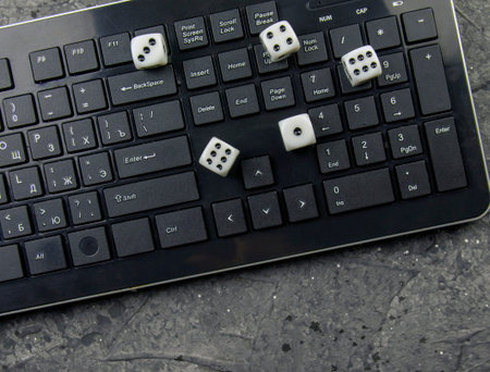 Computer keyboard, game dice on a dark background. Online gambling concept