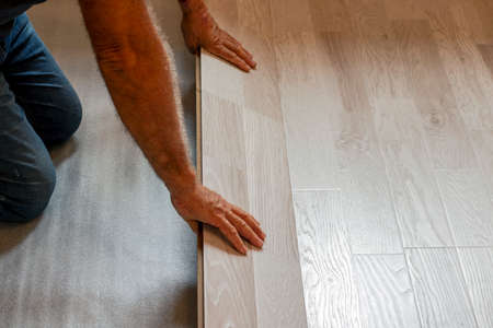 worker lays laminate flooring on a substrate while renovating a houseの写真素材