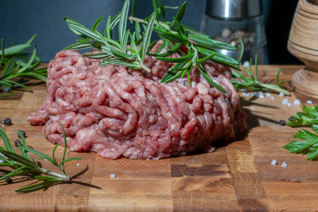 Fresh ground beef, minced meat with herbs and spices on a cutting board.
