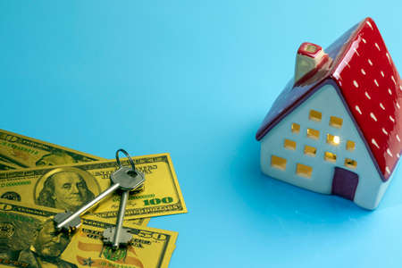House model, money and key on a blue background with copy space. Saving money for new home, home loan, mortgage and real estate business conceptの写真素材