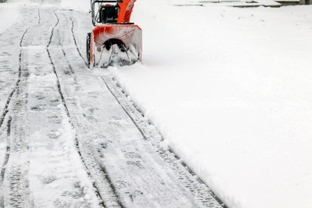 The snow-covered sidewalk is cleared of snowdrifts with the help of mini-snow removal equipment....