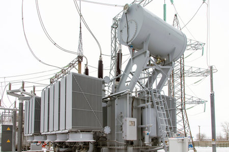 Power transformer at high voltage outdoor electrical substation in winter.