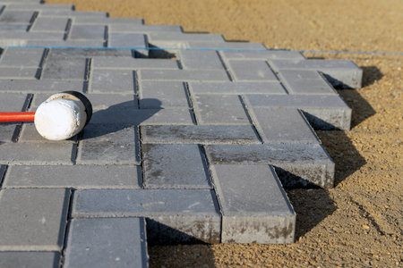 Laying paving stones on a garden path. Laying gray concrete paving slabs on a flat gravel and sand base.の写真素材