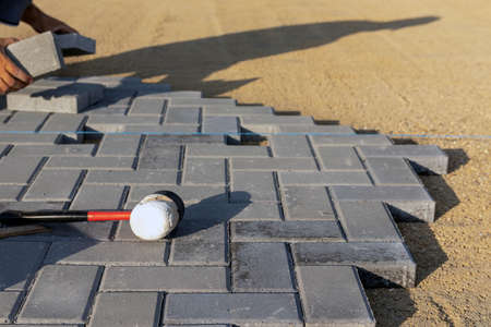 Laying gray concrete paving slabs. Professional bricklayers lay new driveway, sidewalk or patio tile or slabs on a leveled sand base. selective focus.の写真素材