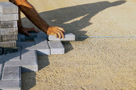 Laying paving slabs close-up. Road surface, construction. Sidewalk repair. A worker lays paving slabs. Laying tiles in the garden of the city park. selective focusの写真素材