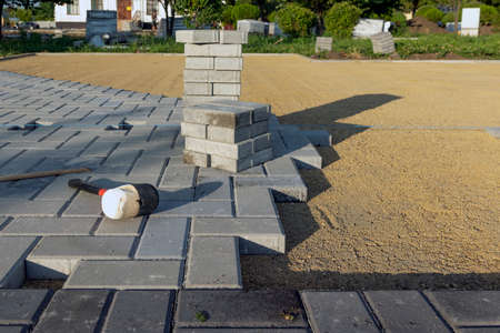 Laying gray concrete paving slabs in the yard on a leveled sand base.の写真素材