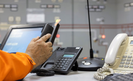 Dispatcher's hand picking up or hanging up the phone with a blurred background in the control room.の写真素材