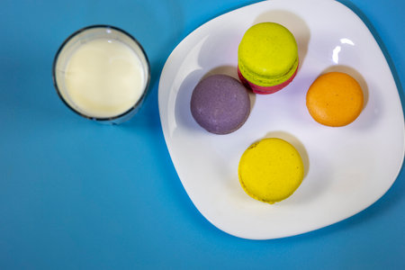 Close-up of a colorful macaroon or macaron with a glass of milk. Sweet and colorful french macaroons with copy space. view from above.の写真素材