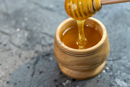 Fresh liquid honey, honey stick on a black background. Wooden utensils with honeyの写真素材