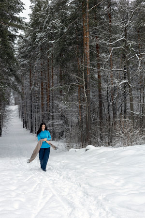 Beautiful woman standing in the winter forest and enjoying the first snow. The concept of winter holidays and sports.の写真素材