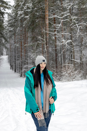 Beautiful woman standing in the winter forest and enjoying the first snow. The concept of winter holidays and sports.の写真素材