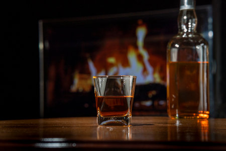 Close-up of a glass of whiskey with chilling stones. There are stone cubes on a wooden table.の写真素材