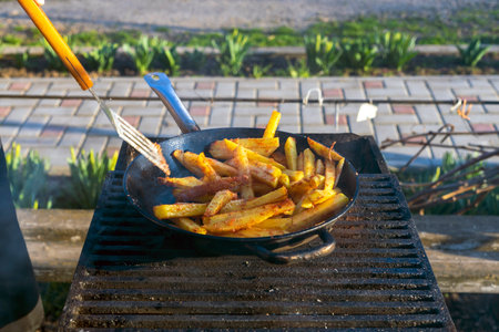 Fry the potatoes in a large saucepan. delicious food in nature. Potatoes fried in oil, street food, picnic in nature.の写真素材