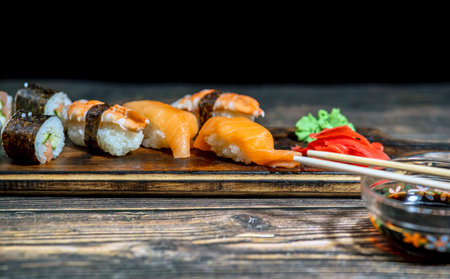 Delicious sushi rolls on serving board and dark background, closeup viewの写真素材