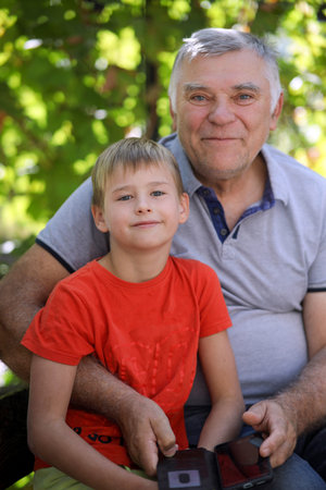 Grandfather and grandson are sitting on a bench in the garden.
