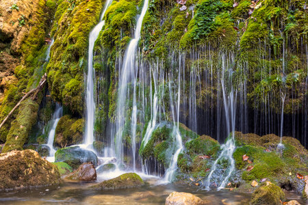 Beautiful landscape of a mountain river with a small waterfall and splashes of water. Fresh water background with fast rapids in a wild river. Wonder of nature, quiet place for green tourism conceptの写真素材