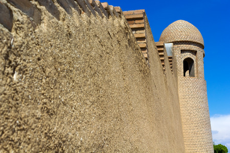 minaret of a mosque and a wall against the blue skyの写真素材