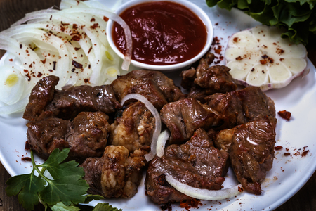 Shish kebab with sauce, onion, garlic and greens. Barbecue. Still life. Rustic. Closeupの写真素材