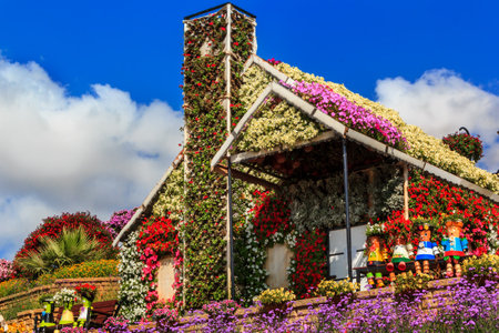 Dubai, UAE - January 5, 2017. Dubai Miracle Garden -Floral house and dolls on the bench. Dubai Miracle Garden is the largest natural flower garden in the world with a wide variety of different colors arranged in a heart shape, star, or other shapes of houのeditorial素材
