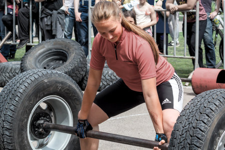 Almaty, Kazakhstan - May 28, 2017. Young girl lifts a heavy barbell. Weightlifting. City fesitwal sport on the street for a healthy lifestyle. Sports contests for arm-wrestling, heavy lifting, tug-of-war, army bench pressのeditorial素材